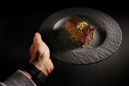 Chocolate cake with walnuts and pistachio isolated on black background. Pastry from homemade bakeryの写真素材