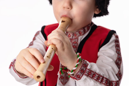 Bulgarian boy in traditional folklore costumes with spring flowers snowdrop and handcraft wool bracelet martenitsa symbol of Baba Martaの写真素材