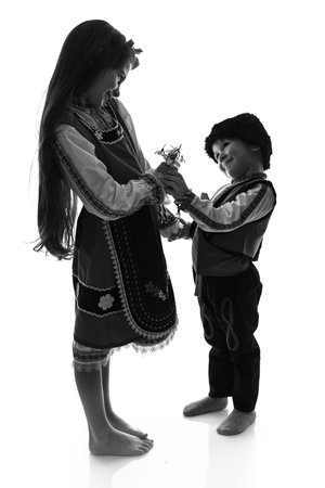 Bulgarian kids boy and girl in traditional folklore costumes with spring flowers snowdrop and handcraft wool bracelet martenitsa symbol of Baba Martaの写真素材