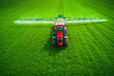 Aerial view of farming tractor plowing and spraying on field.の写真素材
