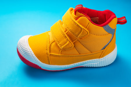 Yellow baby shoes. Kids sport sneakers isolated on blue backgroundの写真素材