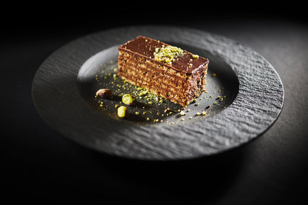 Chocolate cake with walnuts and pistachio isolated on black background. Pastry from homemade bakeryの写真素材