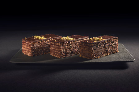 Chocolate cake with walnuts and pistachio isolated on black background. Pastry from homemade bakeryの写真素材