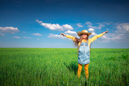 Green wheat field landscape and happy farmer girl playing with straw hatの写真素材