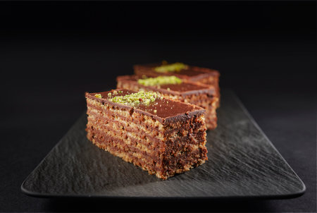 Chocolate cake with walnuts and pistachio isolated on black background. Pastry from homemade bakeryの写真素材