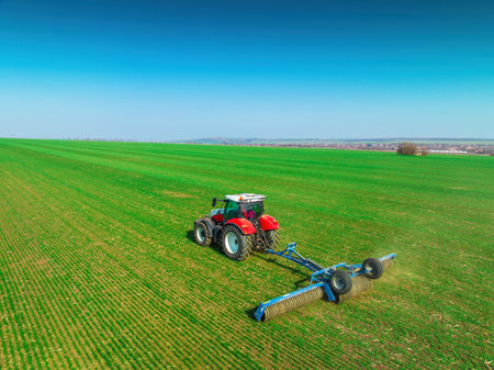Tractor with a roller tillage on spring field. Aerial view of Soil rolling supports germination and is the basis for good harvesting, organic farming and agronomyの写真素材