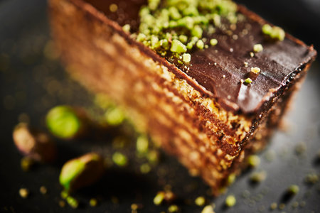 Chocolate cake with walnuts and pistachio isolated on black background. Pastry from homemade bakeryの写真素材
