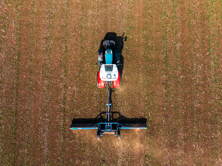 Tractor with a roller tillage on spring field. Aerial view of Soil rolling supports germination and is the basis for good harvesting, organic farming and agronomyの写真素材