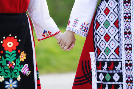 Girls in traditional bulgarian ethnic costumes with folklore embroidery holding hands. The spirit of Bulgaria - culture, history and traditions.の写真素材