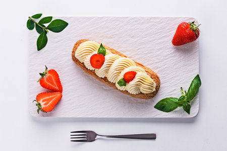 French eclair grazed with chocolate and fruity strawberry cream or sweet Italian profiteroles and fresh juicy strawberries, food on white backgroundの写真素材