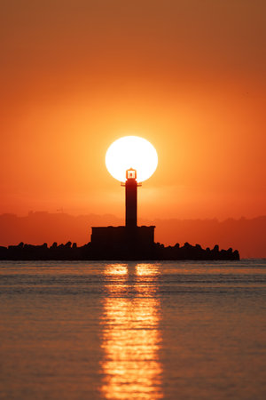 Seascape of sunrise over sea lighthouse and coastal beach shore, Varna, Bulgariaの写真素材