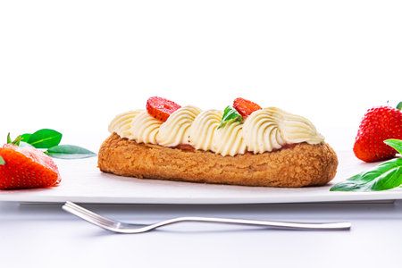 French eclair grazed with chocolate and fruity strawberry cream or sweet Italian profiteroles and fresh juicy strawberries, food on white backgroundの写真素材