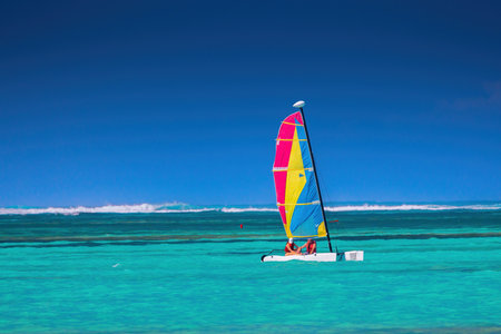 People on a color catamaran sailboat or winsurf sailing in calm caribbean sea, summer vacation and sportの写真素材
