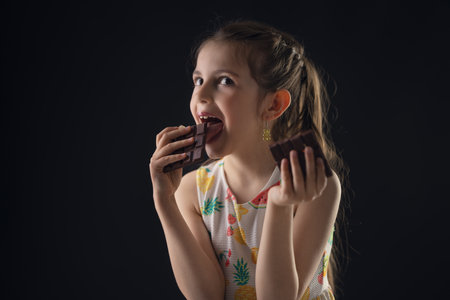 Chocolate and pretty hungry little woman portrait. Beautiful girl ready to eat chocolate bar.の写真素材