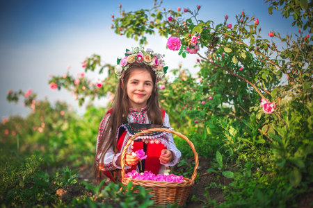 Cute little girl in traditional Bulgarian dress with basket of rosesの写真素材