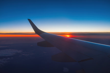 Airplane flight in sunset sky over ocean water and wing of plane. View from the window of the Aircraft. Traveling in air.の写真素材