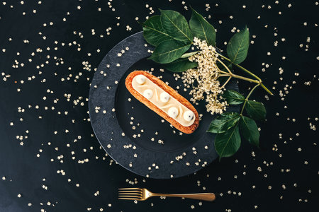 French eclair grazed with chocolate or sweet Italian profiteroles on a black stone plate, gourmet confectionery foodの写真素材