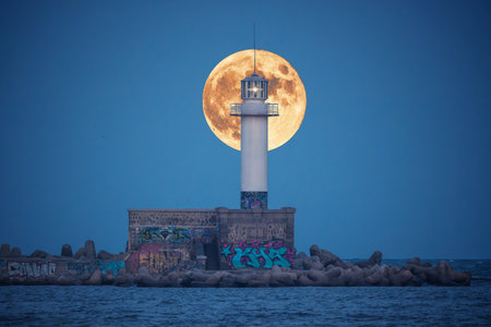 Full moon twilight landscape over sea horizon and lighting lighthouse from the coastの写真素材