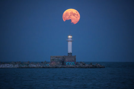 Full moon twilight landscape over sea horizon and lighting lighthouse from the coastの写真素材