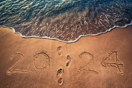Happy New Year 2024 concept written on the sea beach at sunriseの写真素材