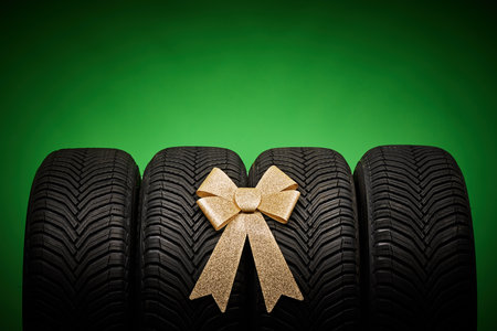 Car tires, new tyres, winter wheels isolated on green background with bow ribbon present.の写真素材