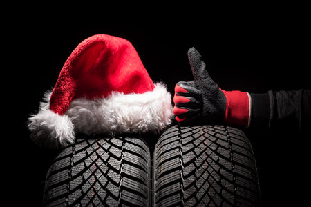 Car tire service and hands of mechanic holding new tyre on black background with copy space for textの写真素材