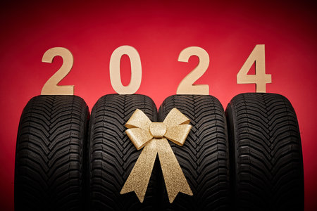 Car tires, new tyres, winter wheels isolated on christmas red background with text happy new year 2024.の写真素材