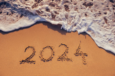 Happy New Year 2024 concept, lettering on the beach. Written text on the sea beach at sunrise.
