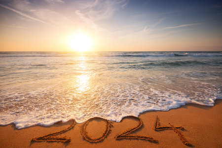 Happy New Year 2024 concept, lettering on the beach. Written text on the sea beach at sunrise.の写真素材