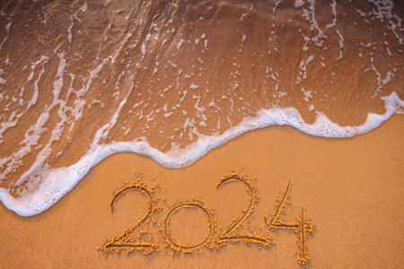 Happy New Year 2024 concept, lettering on the beach. Written text on the sea beach at sunrise.