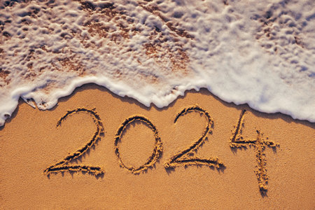Happy New Year 2024 concept, lettering on the beach. Written text on the sea beach at sunrise.の写真素材