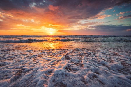 Close up of waves on the beach and a beautiful sunrise over the seaの写真素材