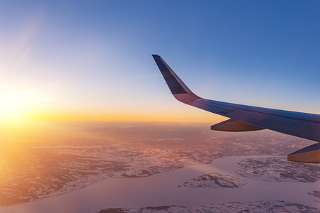Airplane flying low over snowy mountains and preparing for landing to the airport, view from plane window of wing turbine and skylineの写真素材