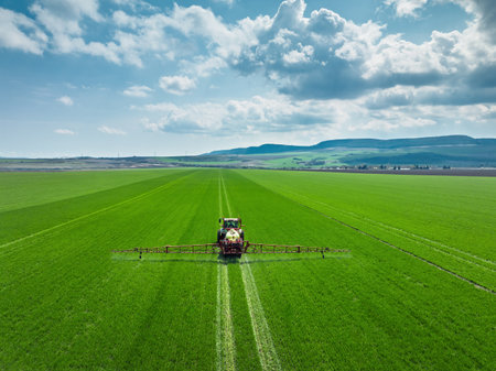 Aerial view of farming tractor plowing and spraying on field.の写真素材