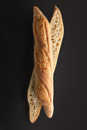 Two French baguettes on black background, top view, copy space