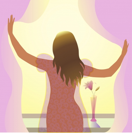 young woman stands near the window in the morning in the rays of the sunの写真素材