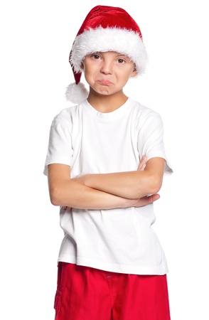 Portrait of unhappy teen boy in Santa hat isolated on white backgroundの写真素材