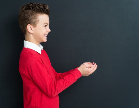 Portrait of adorable young boy 11 years old posing at the black chalkboard in classroom.の写真素材