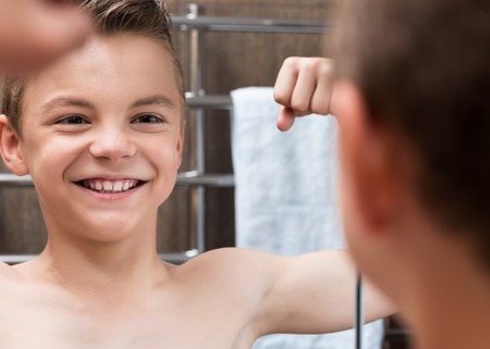 Closeup of a teen boy in the bathroom showing his arm musclesの写真素材