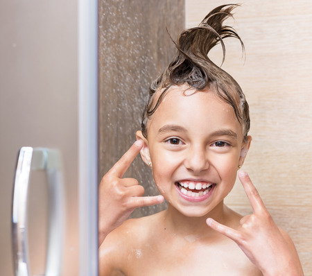 Cheerful beautiful girl bathing under a shower at homeの写真素材