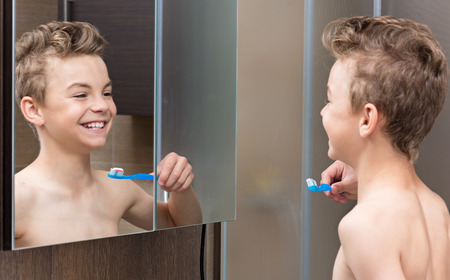 Portrait of a teen boy in the bathroom brushing his teethの写真素材