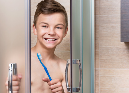 Portrait of a teen boy in the bathroom brushing his teethの写真素材