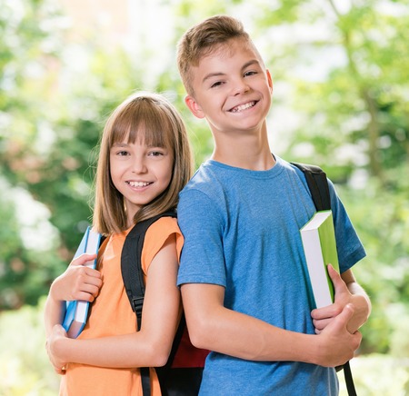 Outdoor portrait of happy teen boy and girl with books. Back to school concept.の写真素材
