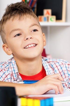 Young boy sitting at desk in the classroom, doing homework at the table. Happy schoolboy - back to...