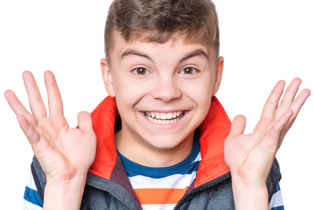 Emotional portrait of caucasian laughing happy teen boy. Handsome smiling amazed or surprised child boy gesturing hands showing large size. Funny cut teenager, isolated on white background.の写真素材
