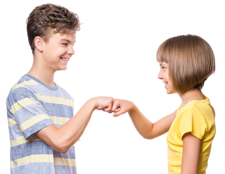 Friendship teen boy and girl are banging their fists. Portrait of happy brother and sister  fist bump isolated on white background. Funny couple children gesturing and greeting.の写真素材
