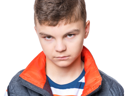Teen boy making silly grimace - expressing disgust face. Upset child isolated on white background. Emotional portrait of caucasian teenager looking at camera.の写真素材