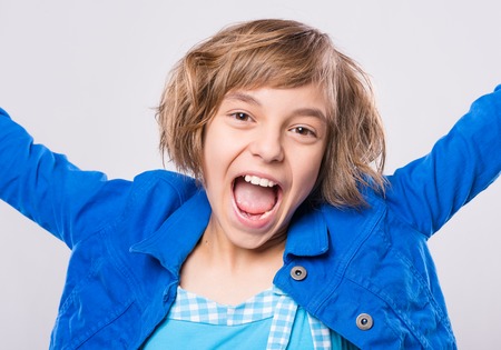 Attractive caucasian girl, on gray background. Schoolgirl smiling and looking at camera. Happy child...