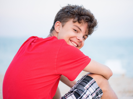 Teen boy on sand on beach - summer vacation, back view. Child looking away.の写真素材