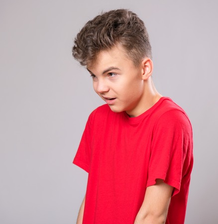 Close up profile emotional portrait of caucasian teen boy. Handsome sad guy. Funny cut teenager on gray background. Child looking away.の写真素材